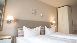 A hotel room with a bed, two wall-mounted lamps, a wardrobe, and two starfish decorations on the wall. - Spalthoff 18, Germany (Sylt)
