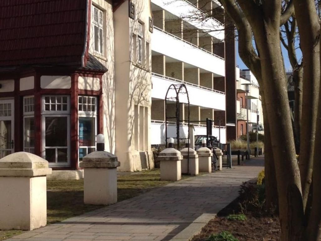 A pathway leading to a building with a traditional facade and a modern structure in the background.