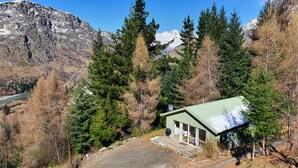 A cabin with a green roof, surrounded by dense forest and mountains. - Entire 2 bedroom detached chalet, in private woodland with valley views. (Arthurs Point)