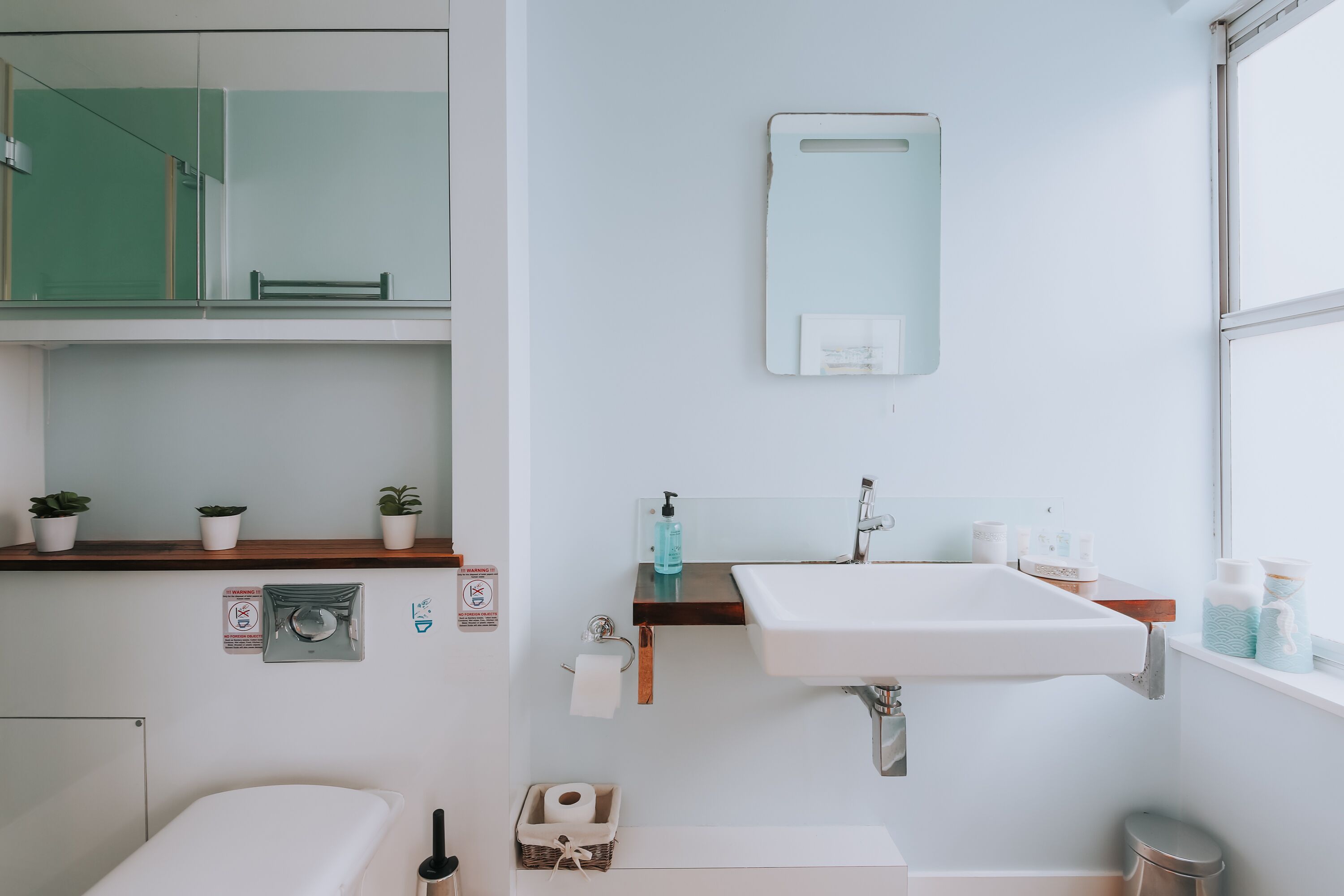Une salle de bain moderne avec un lavabo blanc, un miroir et une fenêtre.