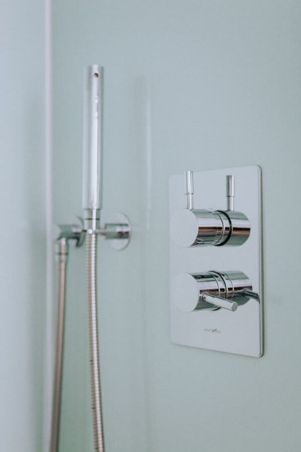 A shower with a chrome faucet and hose, mounted on a light-colored wall. - The Penthouse (Newquay)