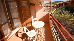 Varanda com mesa e cadeiras, porta de correr e vista para uma área residencial.