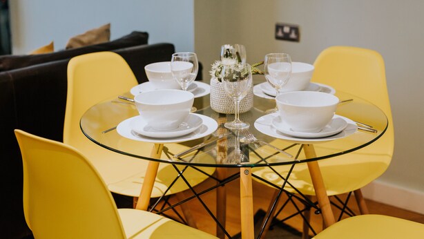Une table à manger avec des bols et des verres blancs, entourée de chaises jaunes.