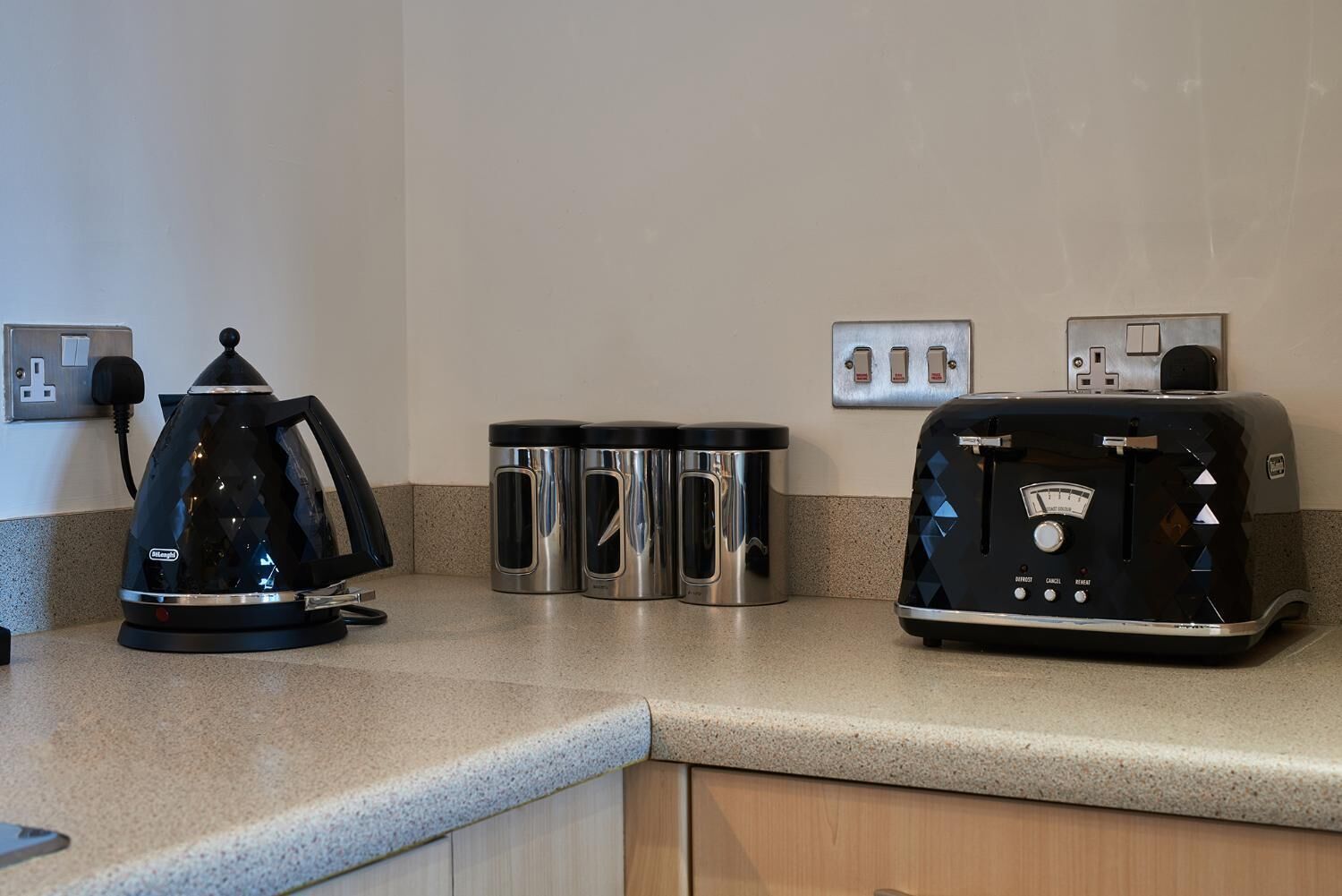 Eine Küche mit Kaffeemaschine, zwei Edelstahlbechern und einem Toaster.