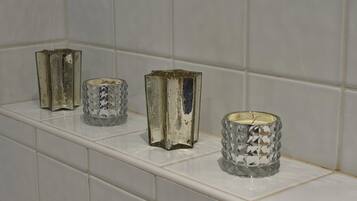 Three glass candle holders on a white tiled shelf.