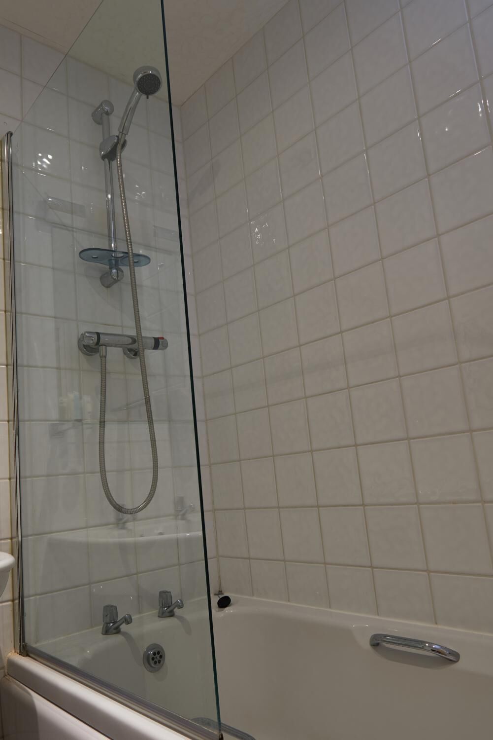 A glass-enclosed shower area with a bathtub.