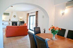 A dining area with a wooden table, black chairs, and a vase of orange flowers. - Casa Linda, comfortable villa with private pool (Porches)