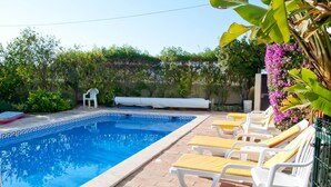 Une piscine avec des chaises longues et un espace de repos abrité.