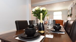A dining table set with black bowls, plates, and a bottle of champagne. - Honeysuckle House (Chester)