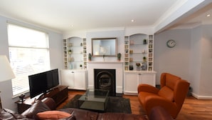 A living room with a fireplace, a television, and a sofa. - Honeysuckle House (Chester)