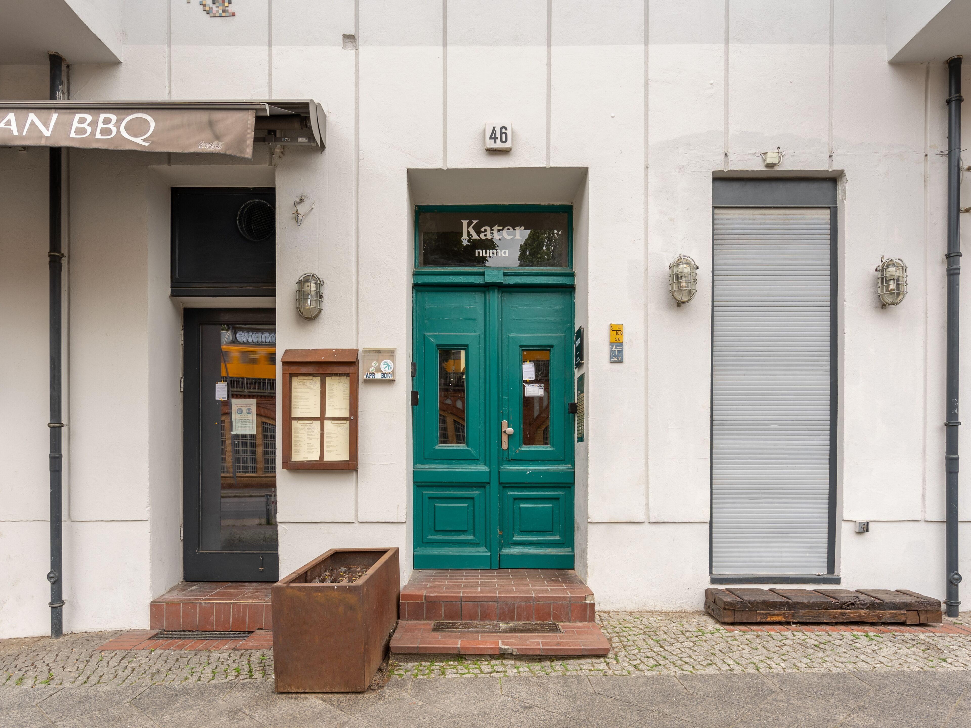 Um edifício com uma porta verde, um toldo fechado e um letreiro de bar.