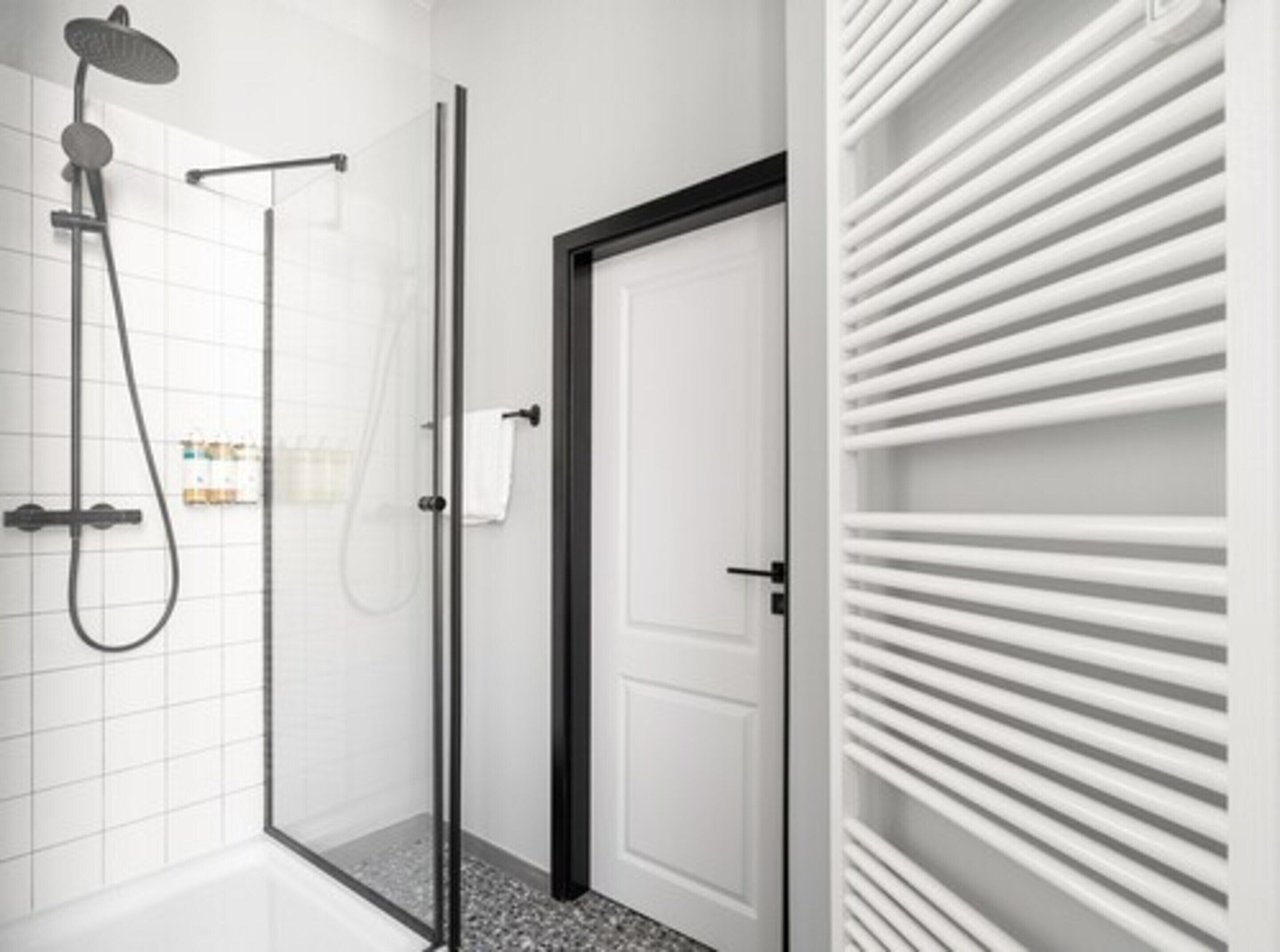 Une salle de bain moderne avec une douche à parois de verre, une porte blanche et un porte-serviettes intégré.