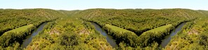 Une rivière traverse une vallée boisée, bordée de collines escarpées de part et d’autre.