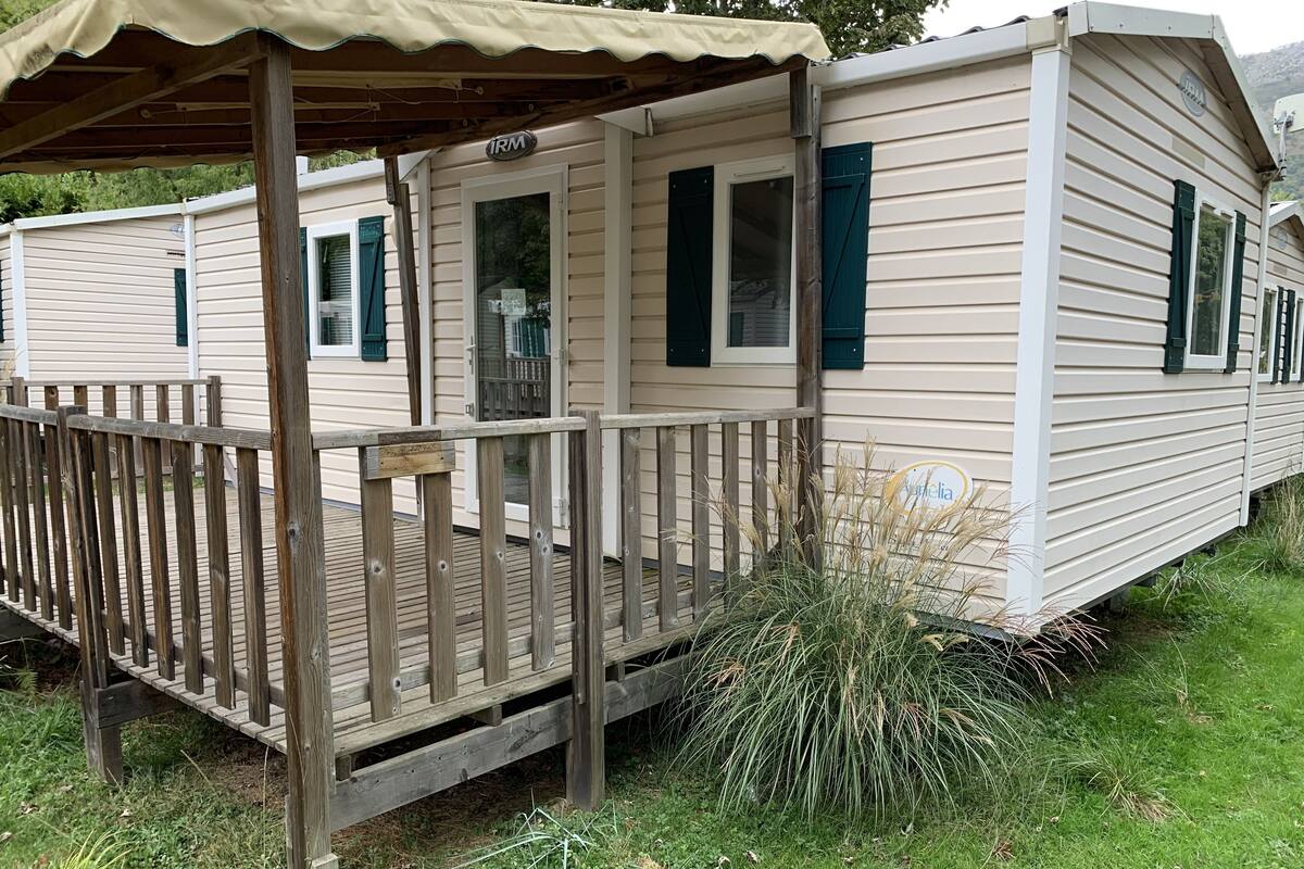 Een stacaravan met een houten terras en een overdekte veranda.