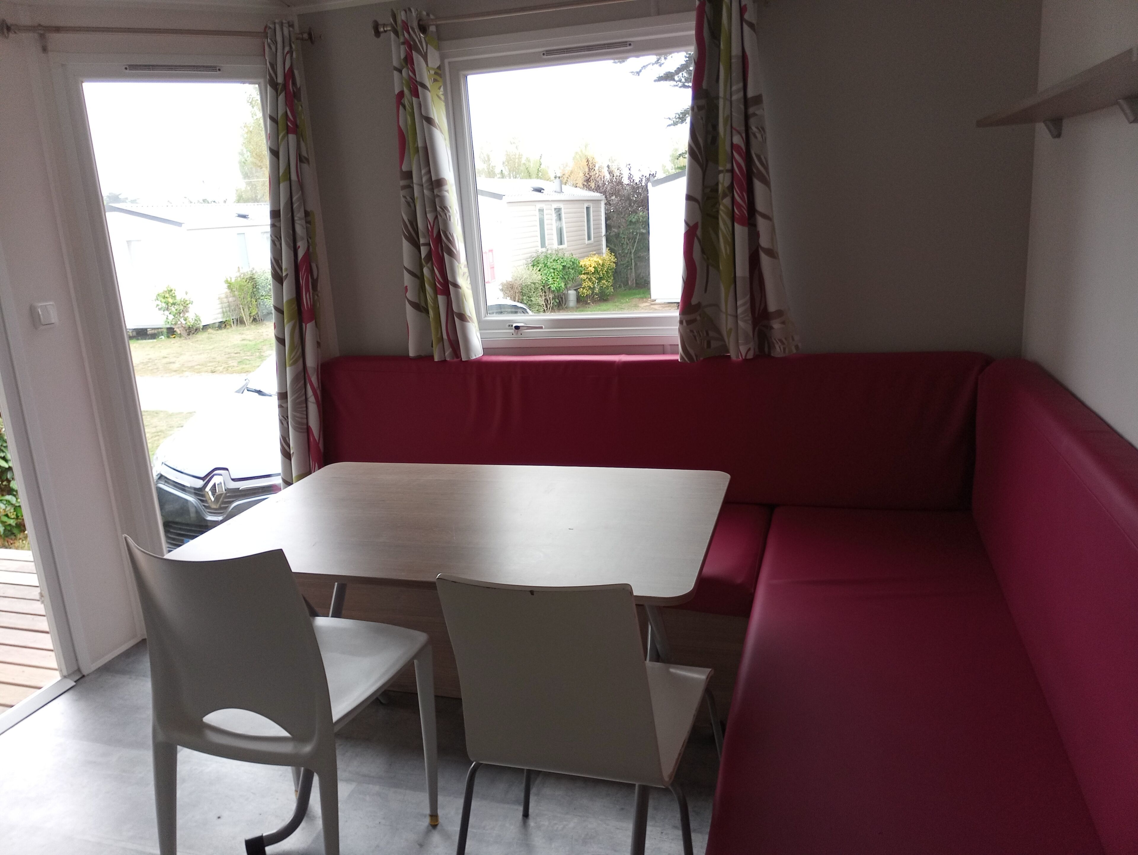 Una habitación con un sofá rojo, una mesa blanca y dos sillas blancas.