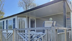 Een houten terras met een balustrade, een overdekte veranda en een stoel.