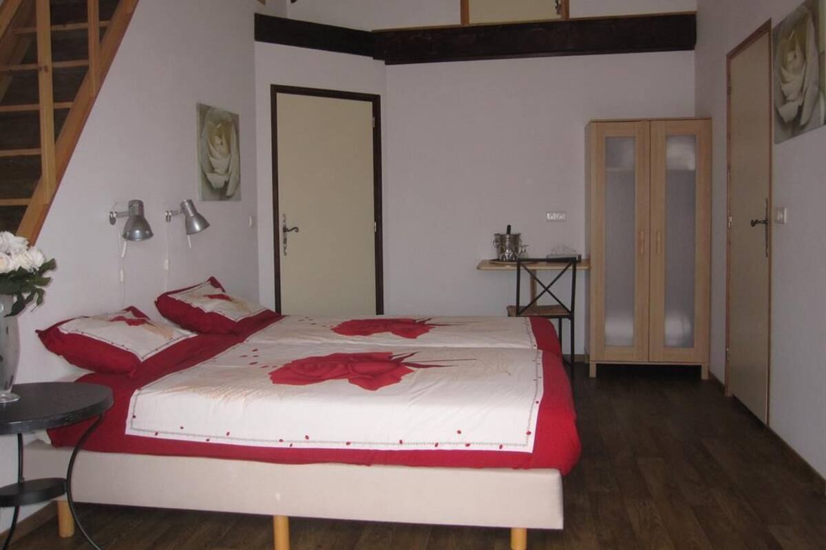 Een slaapkamer met een bed, een bureau, een stoel, een lamp, een deur en een trap.
