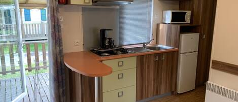 A compact kitchen with a gas stove, a microwave, and a refrigerator.