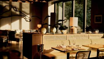 Un comedor moderno con una mesa larga, asientos acolchados y grandes ventanales con vistas a zonas verdes.