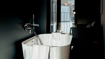 Un baño moderno con una bañera independiente, una toalla y una ventana con vistas al exterior.