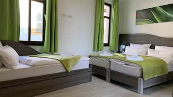 Een hotelkamer met twee bedden, groene gordijnen, een wandcontactdoos en een schilderij.