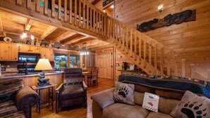 A wooden cabin interior with a staircase, a kitchen area, and a seating area with a couch and chairs. - Cherry On Top | Cherry Log, GA (Blue Ridge)