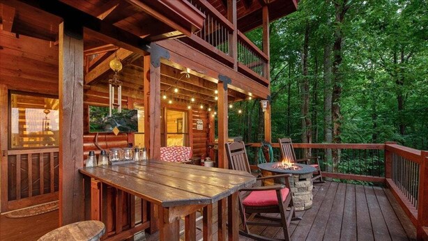A wooden deck with outdoor seating, a fire pit, and a view of the surrounding forest. - Cherry On Top | Cherry Log, GA (Blue Ridge)
