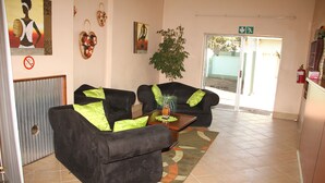 Un área de recepción con dos sofás negros, una mesa de centro de madera y una planta verde.