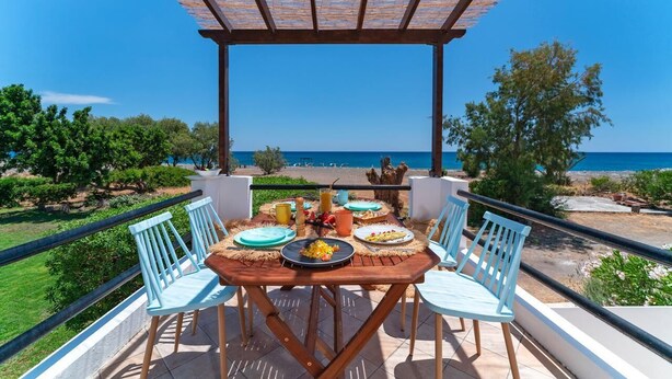 A wooden table with chairs and a view of the sea. - Eco Beachfront Villa (Gennadi)