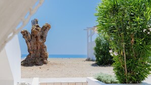 A staircase leading to a beach area with a white structure and a tree trunk. - Eco Beachfront Villa (Gennadi)