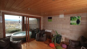 Una habitación acogedora con techo de madera, un jacuzzi y vistas a un paisaje montañoso.