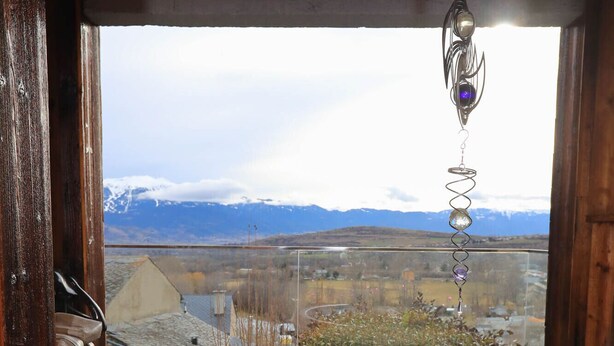 Un jacuzzi en una terraza de madera con vistas a una cadena montañosa nevada.