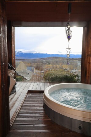 Relax on the deck overlooking the majestic mountain landscape, where a hot tub awaits.