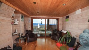 Una habitación acogedora con paredes y techo de madera, un jacuzzi y vistas a las montañas.