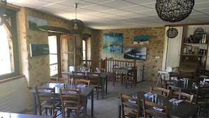 Un ristorante con tavoli e sedie di legno, pareti in pietra e opere d'arte alle pareti.