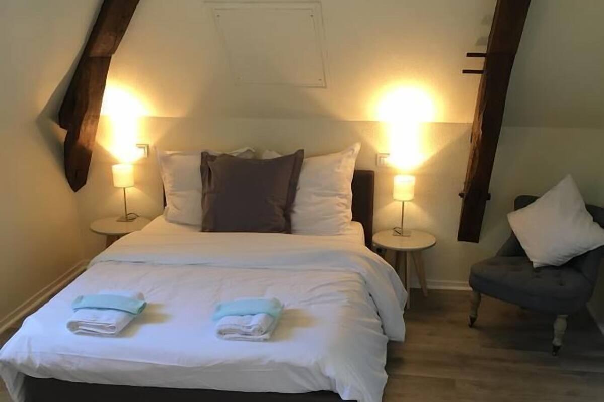 Un dormitorio con una cama, dos mesitas de noche y una silla.