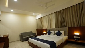 Une chambre d’hôtel avec un grand lit, un canapé, un bureau et un ventilateur de plafond.