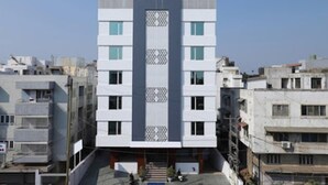 Un immeuble moderne à plusieurs étages, doté d’un élément vertical central, et entouré d ’autres bâtiments résidentiels.