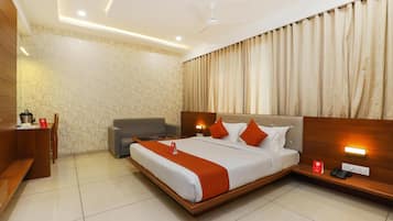 A hotel room with a large bed, a desk, a chair, and a sofa.