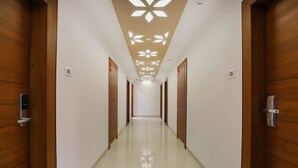 Un long couloir étroit, avec des portes en bois de chaque côté et un plafond orné d’un motif géométrique.