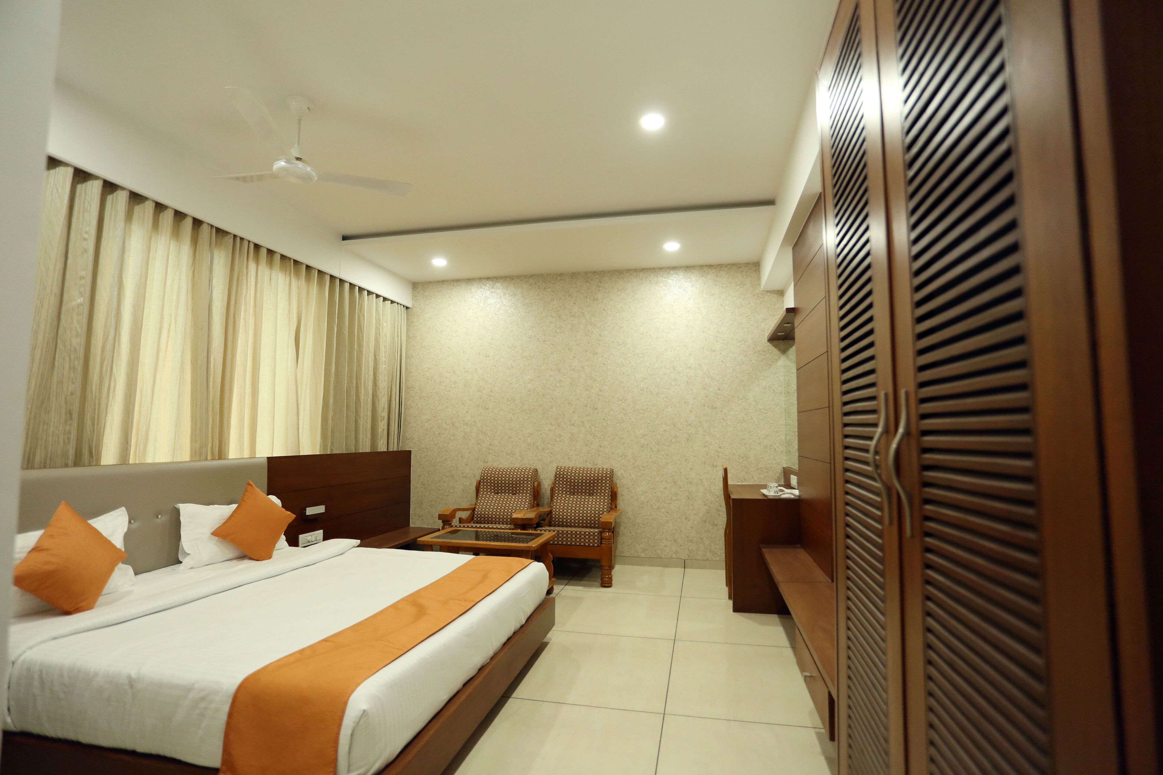 A hotel room with a bed, two chairs, a desk, and a wardrobe.