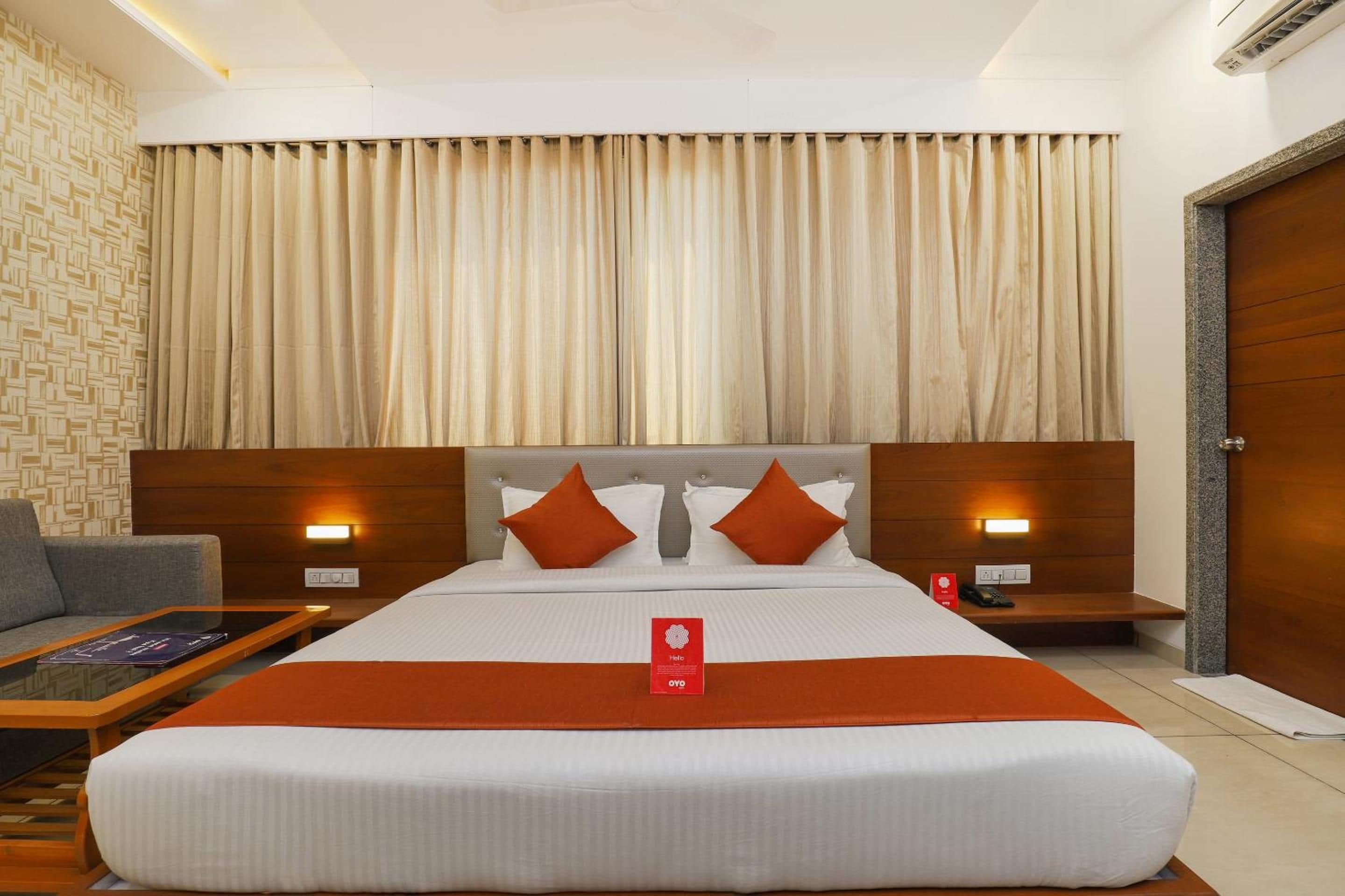 A hotel room with a large bed, two bedside tables, a sofa, and a patterned wall.