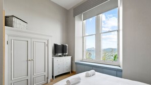 A bedroom with a bed, a television on a dresser, and a window with a view of the outdoors. - No 3 Lomond Castle - Sleeps 4 - sleeps 4 guests  in 2 bedrooms (ALEXANDRIA)