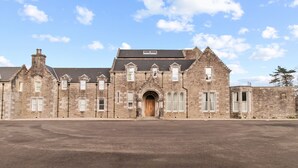 A historic stone building with a central arched entrance, multiple windows, and a flat roof. - No 3 Lomond Castle - Sleeps 4 - sleeps 4 guests  in 2 bedrooms (ALEXANDRIA)