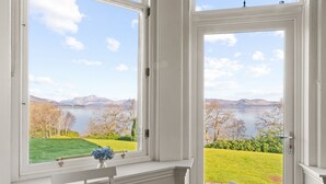 A room with a large window offering a view of a lake and mountains. - No 3 Lomond Castle - Sleeps 4 - sleeps 4 guests  in 2 bedrooms (ALEXANDRIA)