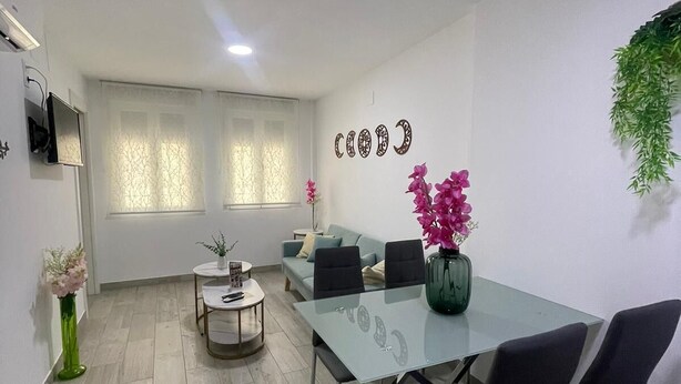 A modern meeting room with a glass table, black chairs, a sofa, and decorative plants. - Viana Rooms (Córdoba)