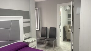 A bedroom with a bed, a nightstand, two chairs, a wardrobe, and a door leading to another room. - Viana Rooms (Córdoba)
