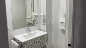 A modern bathroom with a white sink, a mirror, a towel rack, and a hairdryer. - Viana Rooms (Córdoba)