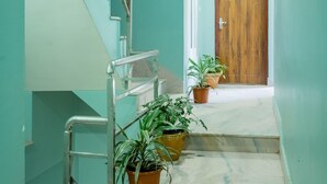 A hallway with a staircase, potted plants, and a wooden door at the end. - Hotel Nepal Bhumi (Kathmandu)