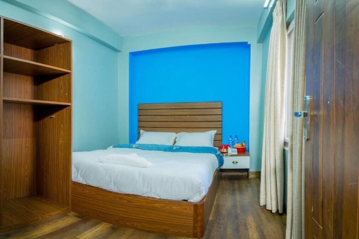 Une chambre à coucher avec un lit en bois, une table de chevet, une armoire et un mur d’accent bleu.